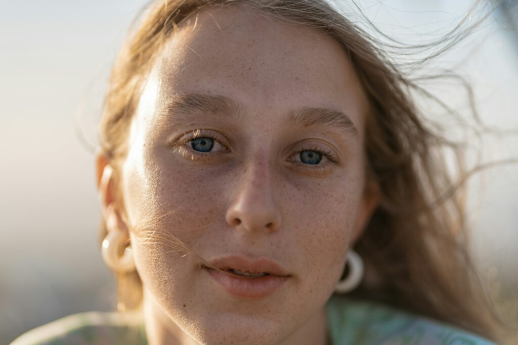Portrait d’une femme à la peau naturelle, éclairée par la lumière du soleil.